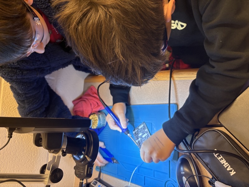 Students learning soldering at the electronics station in the Vienna.i.Lab
